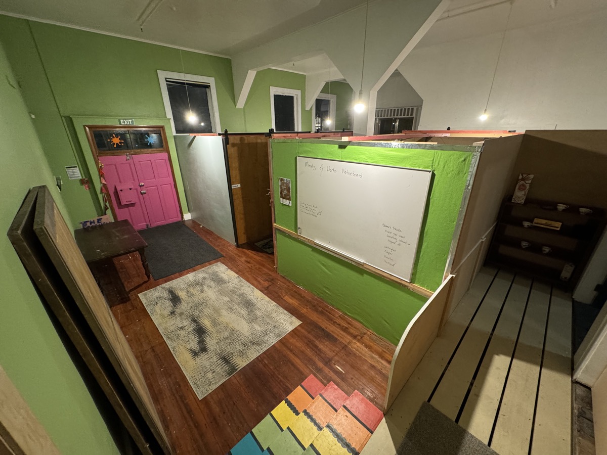 Green-walled studio room with pink double doors, timber floors and partitioned studio spaces