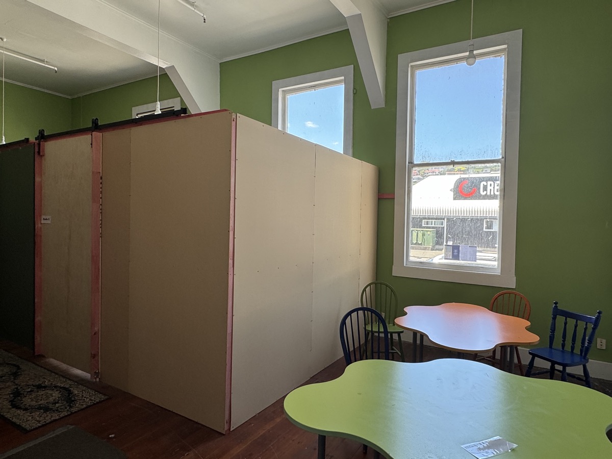 Bright studio area with tall windows, partition walls and colourful tables and chairs